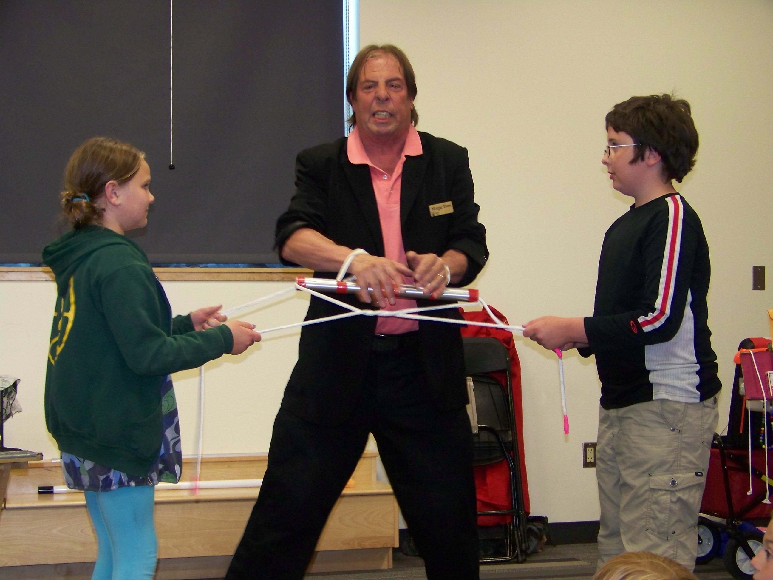 A man and two children joyfully play a magic performance