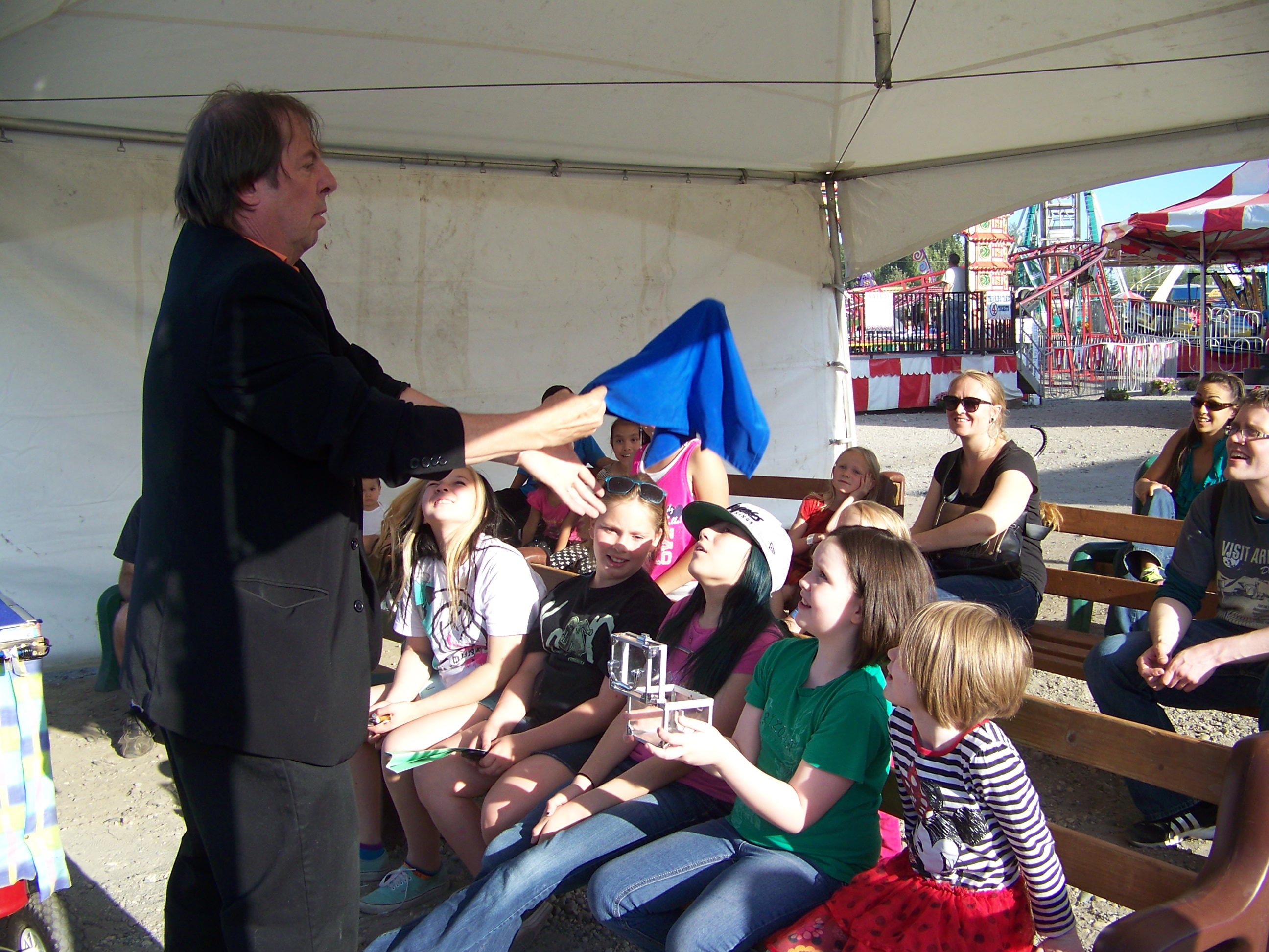 A man holds a blue shirt while performing a magic trick